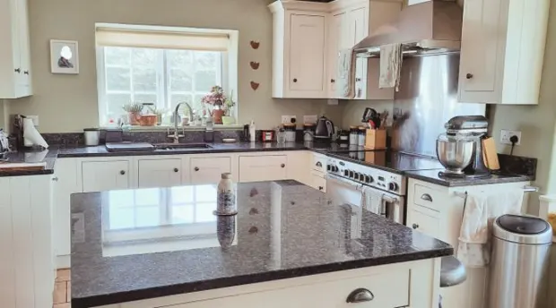 Kitchen with cream cupboards and a dark island worktop