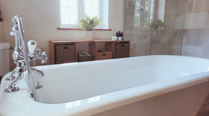 Indulge in luxury! Immaculate bathroom in Warminster, Wiltshire with a breathtaking standalone bath and sleek marble walk-in shower being meticulously cleaned.